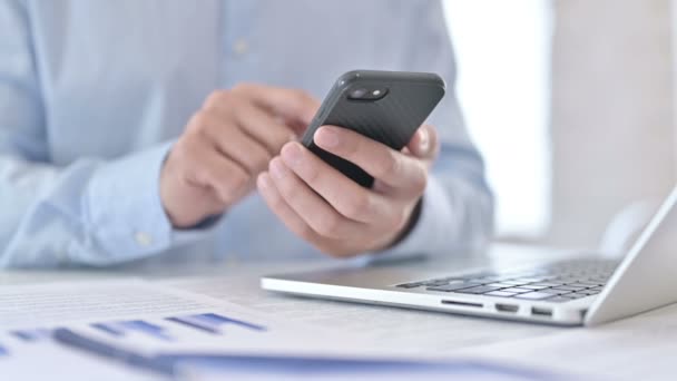 Gros plan d'un jeune homme utilisant un téléphone intelligent dans un bureau moderne — Video