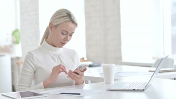 Jovem empresária usando smartphone no escritório — Vídeo de Stock