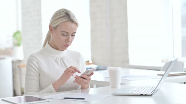 Ofiste akıllı telefon kullanan genç iş kadını hayal kırıklığına uğradı — Stok video