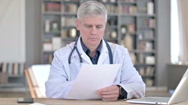 Professional Middle Aged Doctor Reading Documents while Sitting in Office — Stock Video