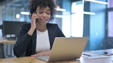 Neşeli Afrikalı İş Kadını İş yerinde Akıllı Telefonla Konuşuyor