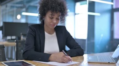 Ofiste çalışırken kağıtları yazan neşeli Afrikalı İş kadını