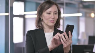 Akıllı telefon kullanan neşeli orta yaşlı iş kadınının portresi