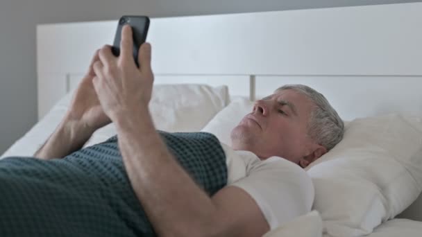 Middeleeuwen Man met behulp van Smartphone tijdens het slapen in bed — Stockvideo