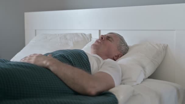 Больной мужчина средних лет, у которого болит спина, когда он спит в постели — стоковое видео