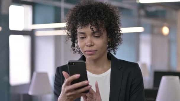 Retrato de Empresaria africana conmocionada reaccionando a la pérdida en Smartphone — Vídeo de stock