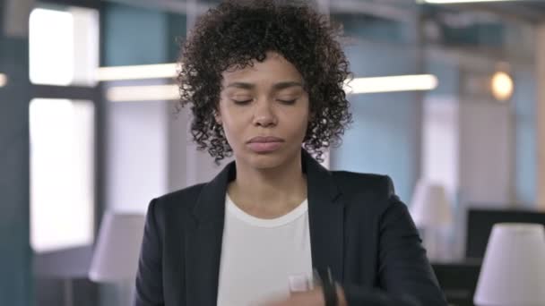 Retrato de una empresaria africana ansiosa esperando a alguien mientras revisa su reloj inteligente — Vídeo de stock