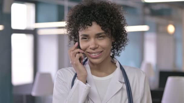 Portret profesjonalnego młodego lekarza uśmiechającego się i mówiącego przez smartfon — Wideo stockowe