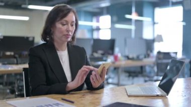 Öfkeli Orta Çağ İş Kadını Ofiste Akıllı Telefon kullanırken Sinirleniyor