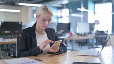 İş yerinde akıllı telefon kullanan ciddi bir iş kadını.