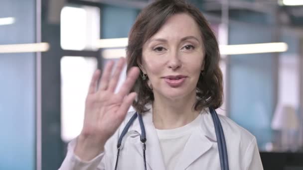 Porträt eines fröhlichen Arztes mittleren Alters, der in die Kamera winkt und freundlich begrüßt — Stockvideo