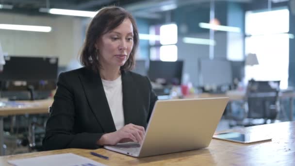 Exitosa mujer de negocios de mediana edad celebrando con el puño trabajando en el ordenador portátil — Vídeo de stock