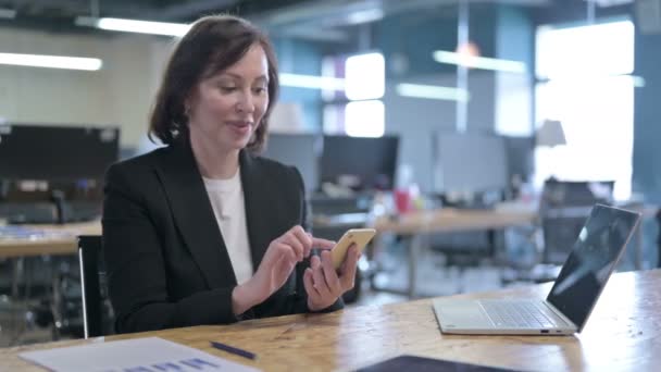 Erfolgreiche Geschäftsfrau mittleren Alters feiert mit Smartphone — Stockvideo