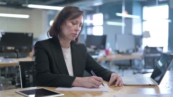 Sérieuse femme d'affaires du Moyen Âge écrivant sur des papiers tout en travaillant au bureau — Video