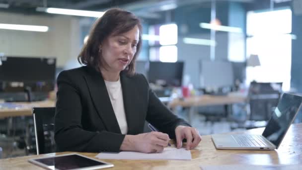 Hårt arbetande medelålders affärskvinna försöker skriva på papper i Office — Stockvideo