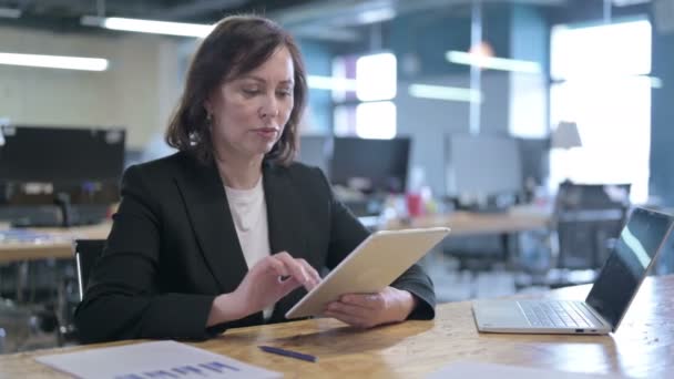 Geschäftsfrau mittleren Alters arbeitet im Büro an Tablet — Stockvideo