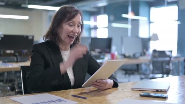 Успешная предпринимательница средних лет празднует во время работы над планшетом — стоковое видео