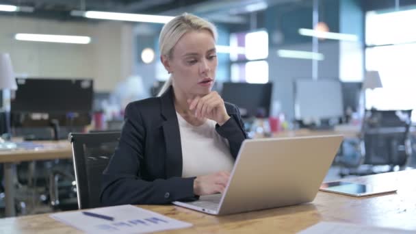Серйозна бізнес-леді мислення та роботи на ноутбуці в офісі — стокове відео