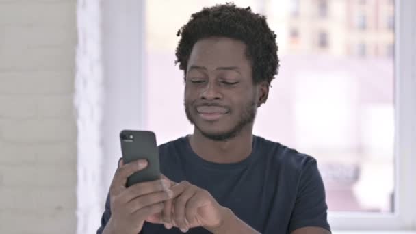 Портрет жизнерадостного молодого афроамериканца с помощью смартфона — стоковое видео