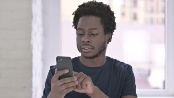 Retrato de alegre jovem afro-americano homem comemorando no smartphone — Vídeo de Stock