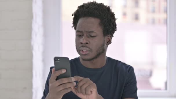 Porträt eines jungen Afroamerikaners schockiert mit Smartphone — Stockvideo