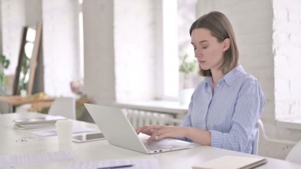 Больная женщина работает над ноутбуком и кашлем в современном офисе — стоковое видео