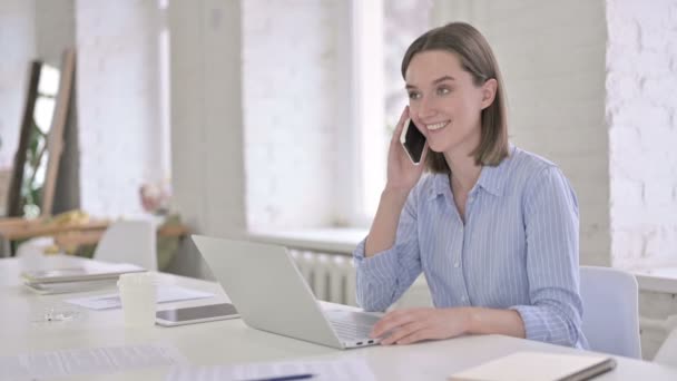 Красива молода жінка розмовляє на смартфоні в сучасному офісі — стокове відео