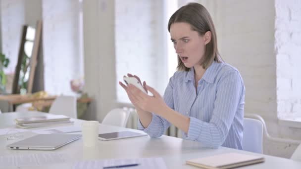 Mujer joven usando el teléfono inteligente y dejándose sorprender — Vídeo de stock