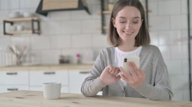 Neşeli genç bayan kahve ile akıllı telefon kullanıyor.