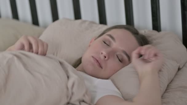 Молодая женщина пытается спать в постели дома — стоковое видео