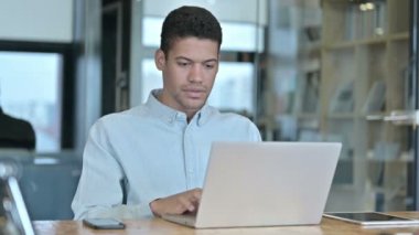 Üzgün Afrikalı genç adam laptopta kaybını anlatıyor.