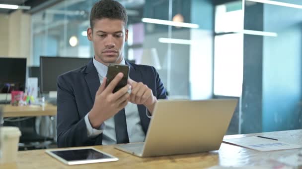 Joven empresario africano usando Smartphone en Modern Office — Vídeos de Stock