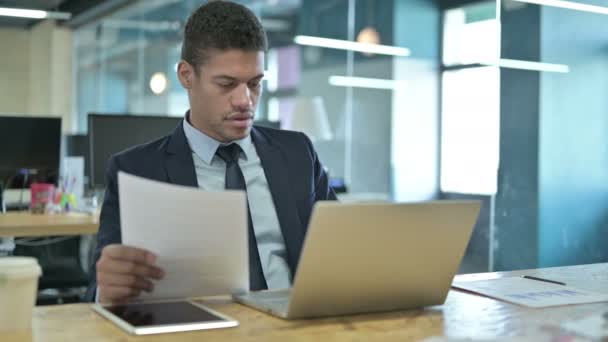 Joven empresario africano trabajando en documentos y computadoras portátiles — Vídeos de Stock