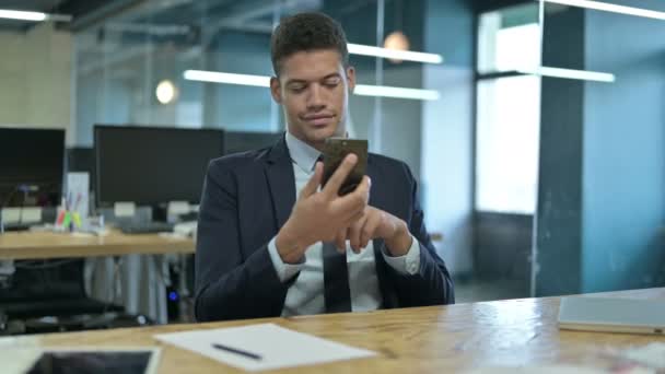 オフィスでスマートフォンを使用している若いアフリカのビジネスマン — ストック動画
