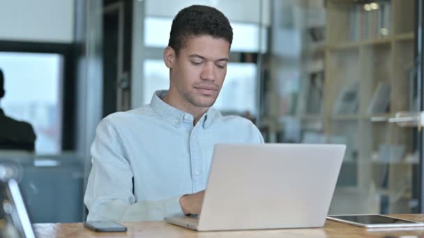 Молодой африканский человек получает удар током по ноутбуку на работе — стоковое видео