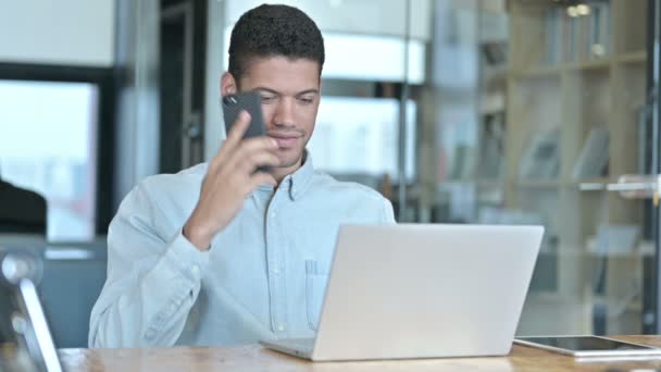 Ung afrikansk man pratar på smartphone på jobbet — Stockvideo