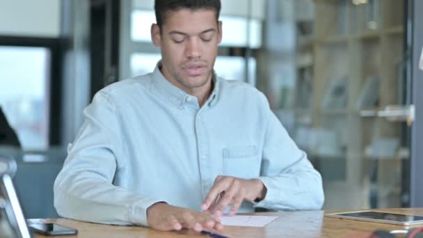 Serieuze Afrikaanse man doet papierwerk in het moderne kantoor — Stockvideo