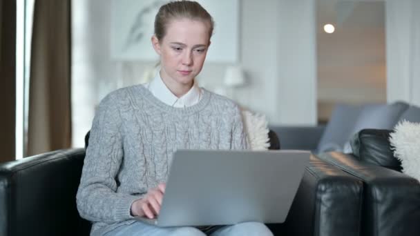 Mujer joven seria que trabaja desde casa en el ordenador portátil — Vídeos de Stock