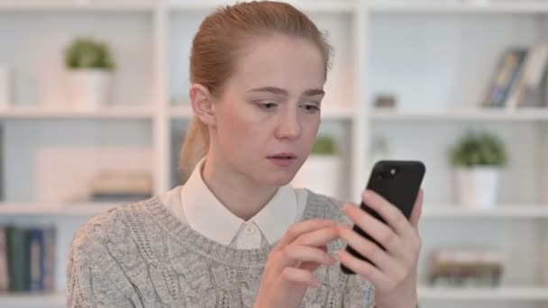 Портрет молодой женщины, реагирующей на потерю на смартфоне — стоковое видео