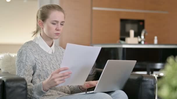 Ung kvinna som arbetar på laptop med dokument hemma — Stockvideo