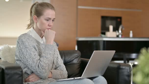 Mujer joven pensando y trabajando en el ordenador portátil en casa — Vídeos de Stock