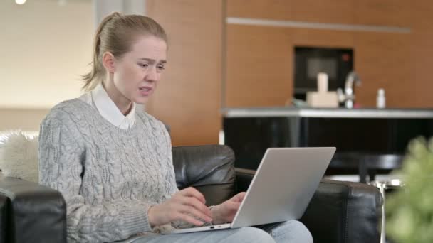 Ung kvinna som reagerar på förlust på laptop hemma — Stockvideo