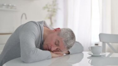 Yorgun yaşlı adam yemek masasında kestiriyor.