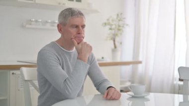 Ciddi kıdemli yaşlı adam evde oturuyor ve düşünüyor.