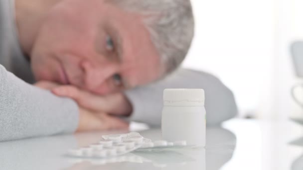 Chory starzec patrzący na lekarstwa na stole — Wideo stockowe