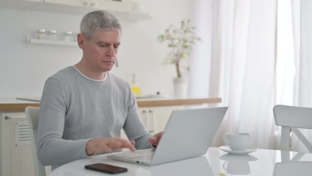 Senior oude man viert succes op laptop thuis — Stockvideo