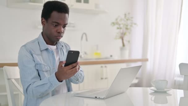 Hombre africano usando Smartphone y Laptop en casa — Vídeo de stock