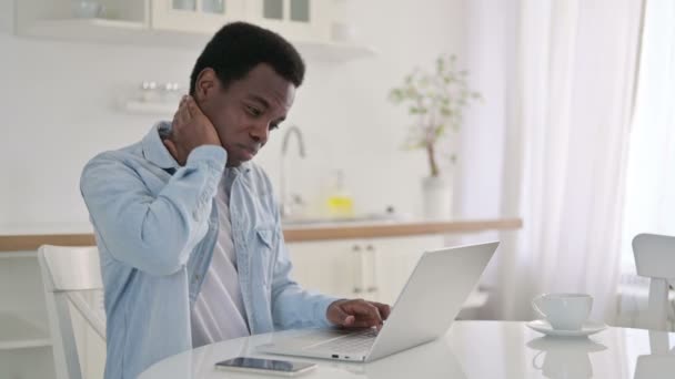 Hombre africano con portátil que tiene dolor de cuello en casa — Vídeo de stock