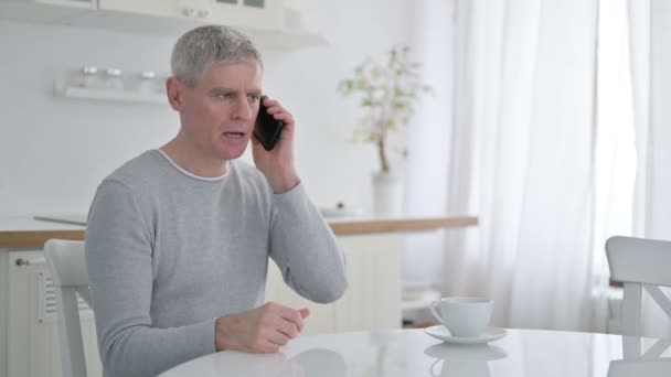 Glada äldre gubben talar på smartphone hemma — Stockvideo