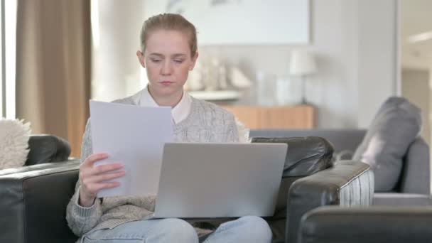 Mladá žena pracuje na notebooku s dokumenty doma — Stock video